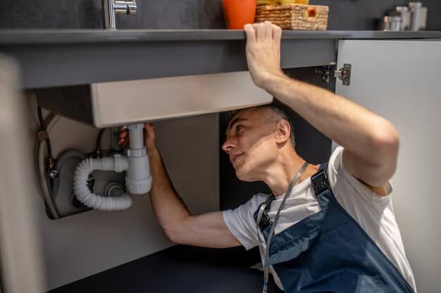 Plumber inspecting a kitchen sink pipe