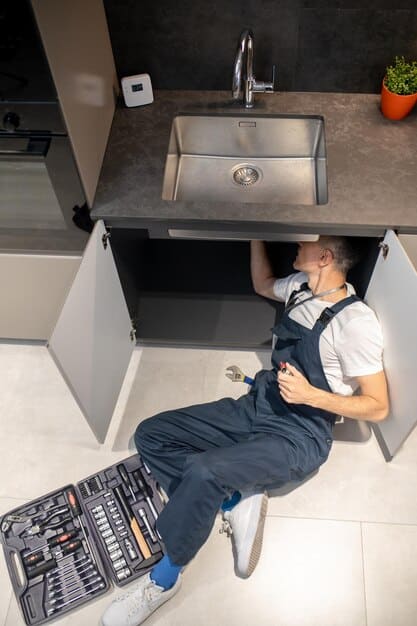Plumber inspecting sink pipes — Second Act Trades