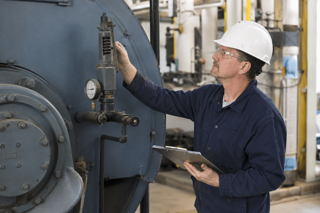 Boiler inspector examining an industrial pressure vessel and safety valve