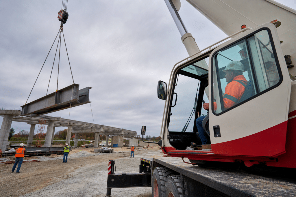 Crane operator controlling a mobile crane while a ground crew guides a lift
